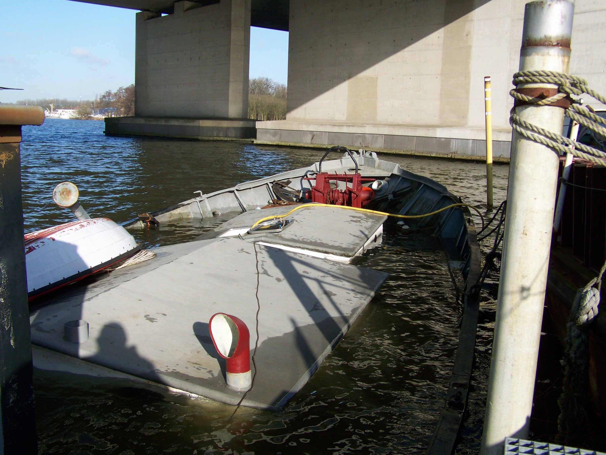 Berging van een gezonken werkboot onder een brug