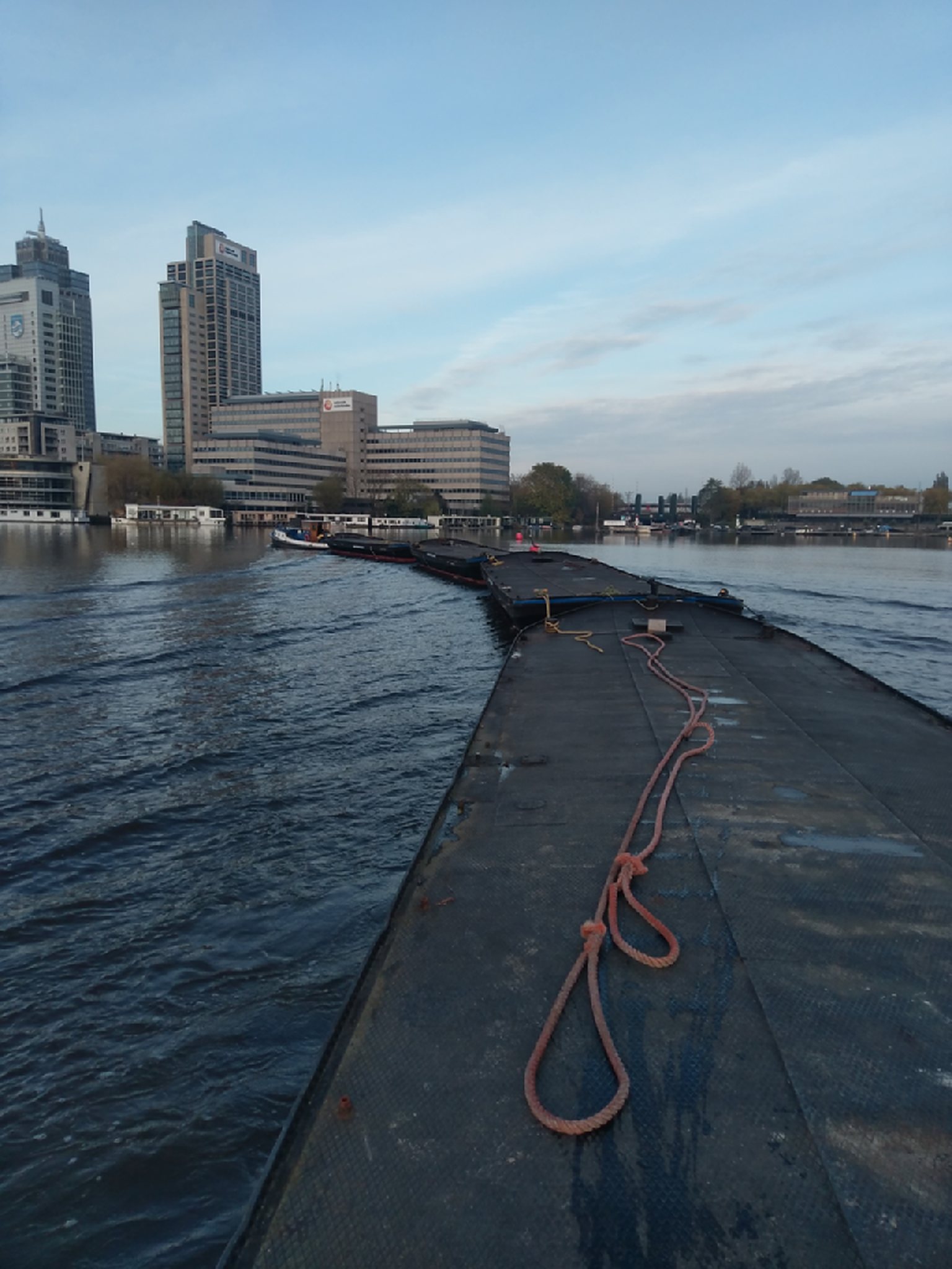 Geduwde bak van Trionaut op het water met de Amsterdamse skyline op de achtergrond